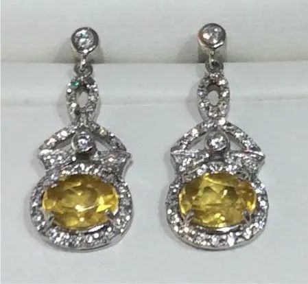 a pair of earrings with yellow stones and diamonds