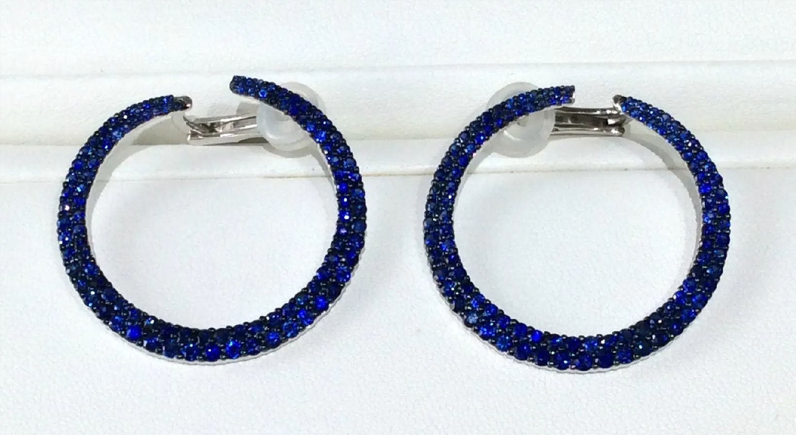 a pair of blue hoop earrings on a white surface