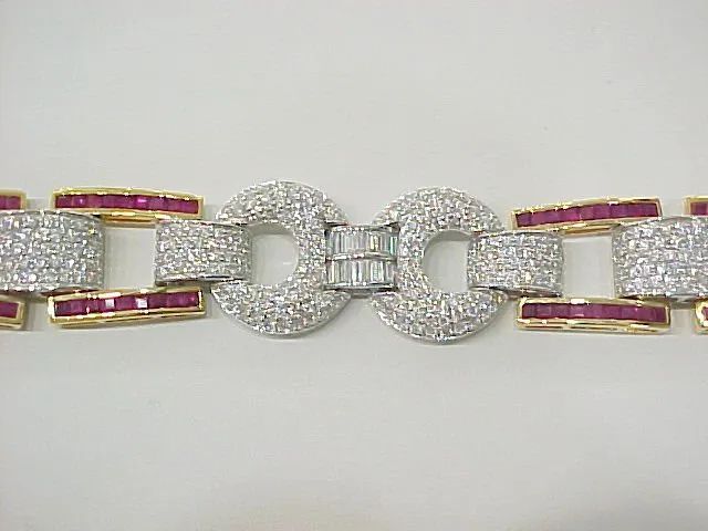 a close up of a bracelet with diamonds and rubies on a white surface