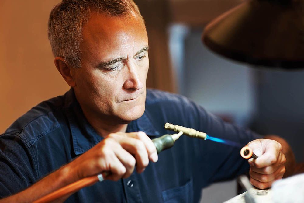a man is working on a piece of metal with a torch.