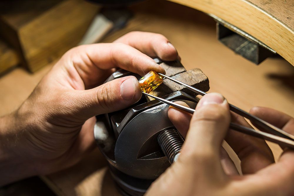 a person is working on a piece of jewelry with tweezers.