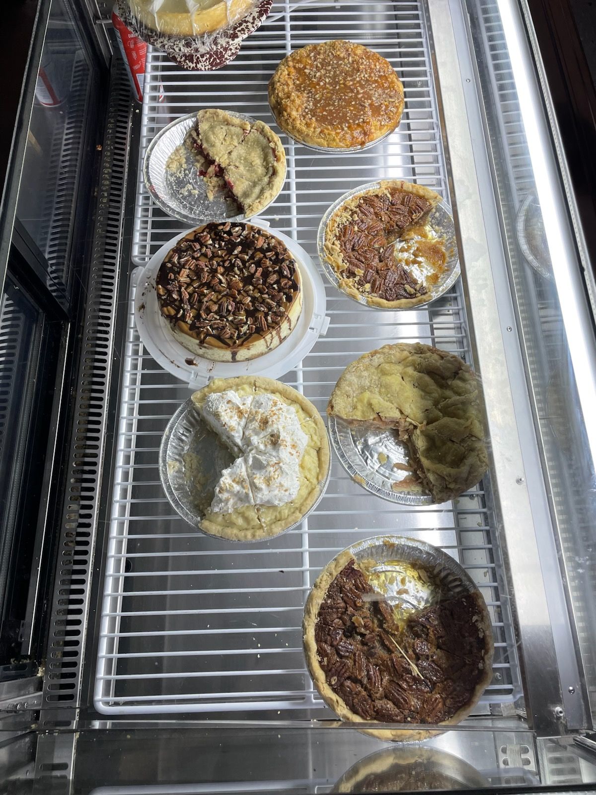Trays of assorted round pastries in a display case, topped with different sweet and savory toppings.