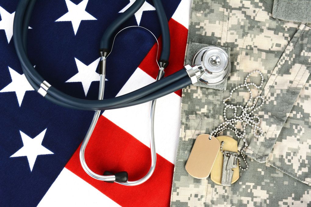 Stethoscope on an American flag beside a camouflage uniform and dog tags