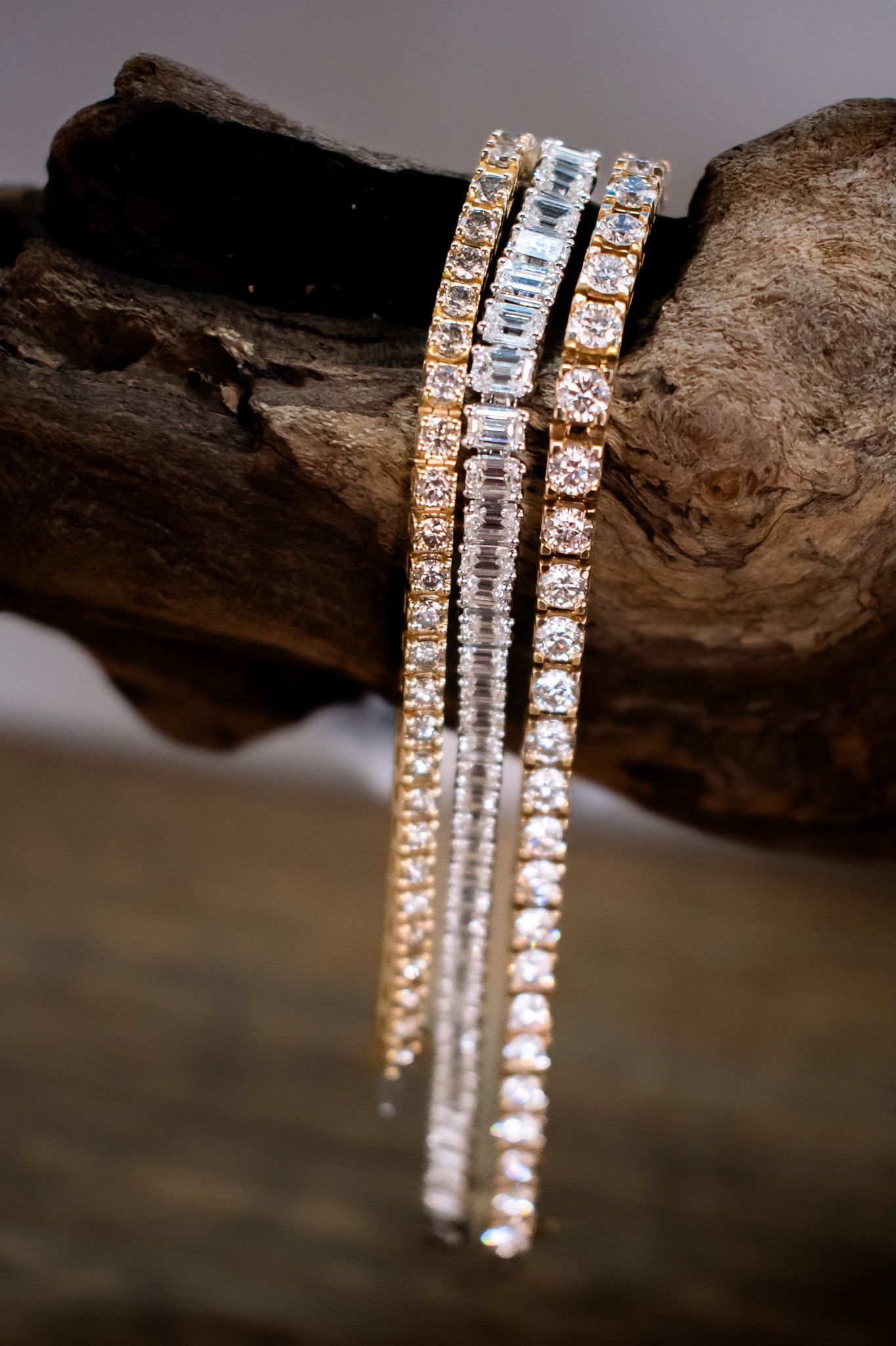 Three bracelets are stacked on top of each other on a piece of wood.