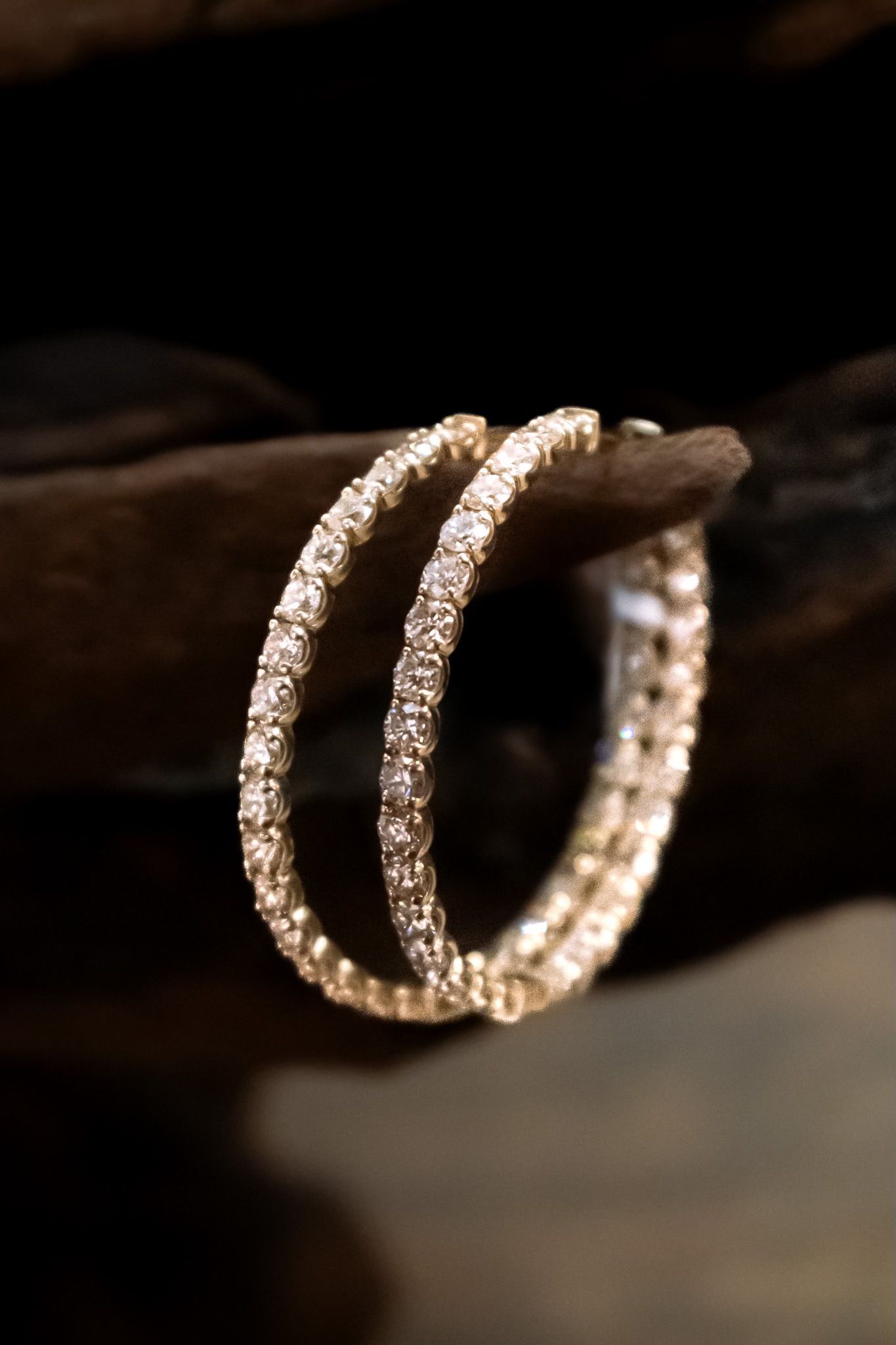 A pair of hoop earrings are sitting on a piece of wood.