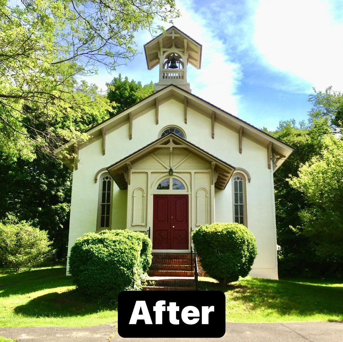 A small white church with a red door and a bell tower