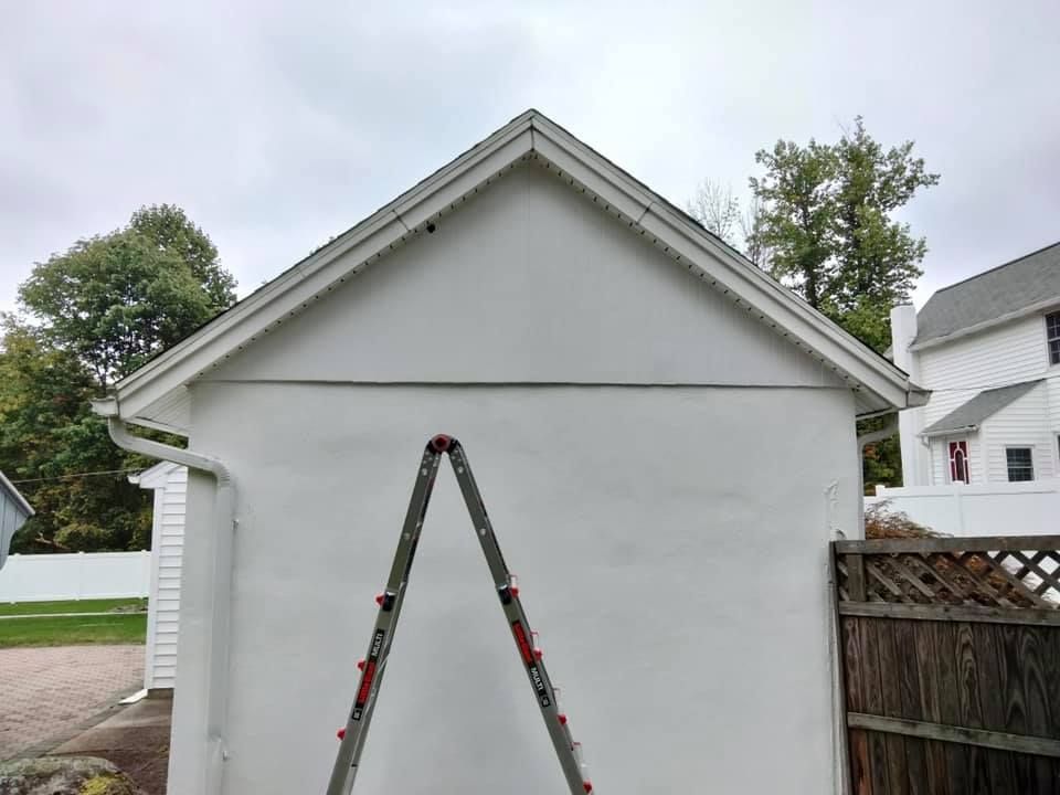 A ladder is sitting on the side of a white building.