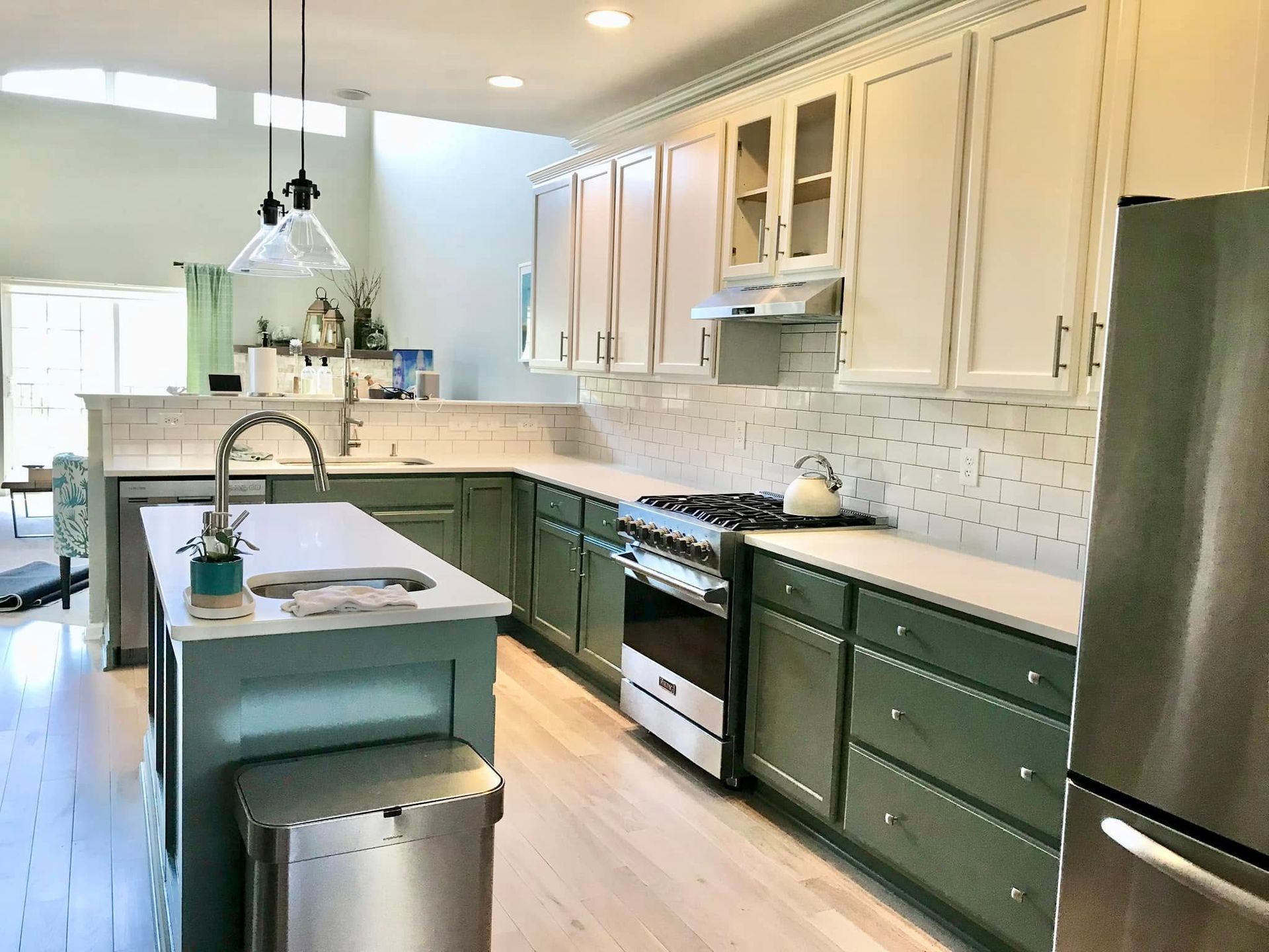 A kitchen with green cabinets and stainless steel appliances