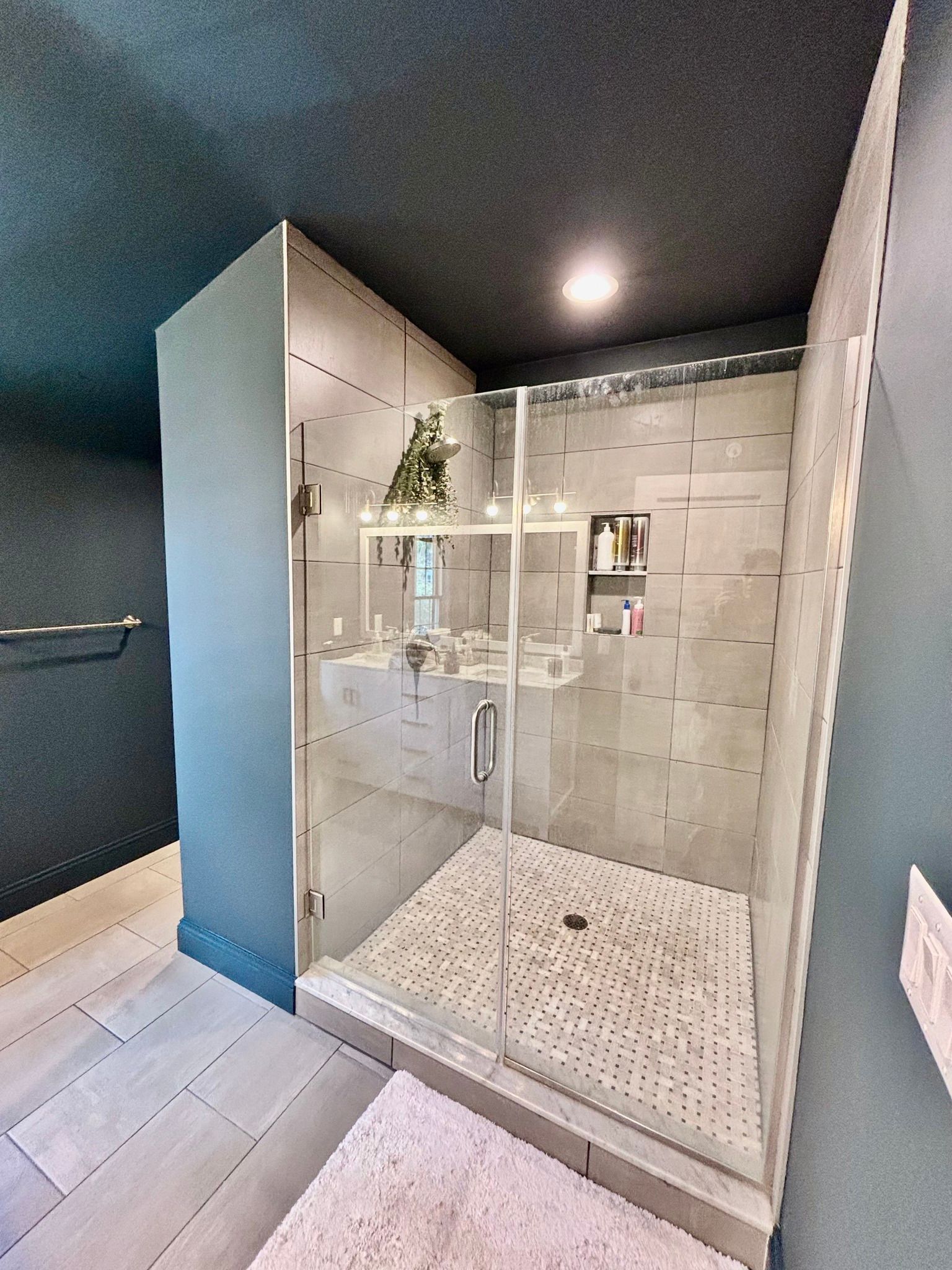 A bathroom with a walk in shower with a glass door.