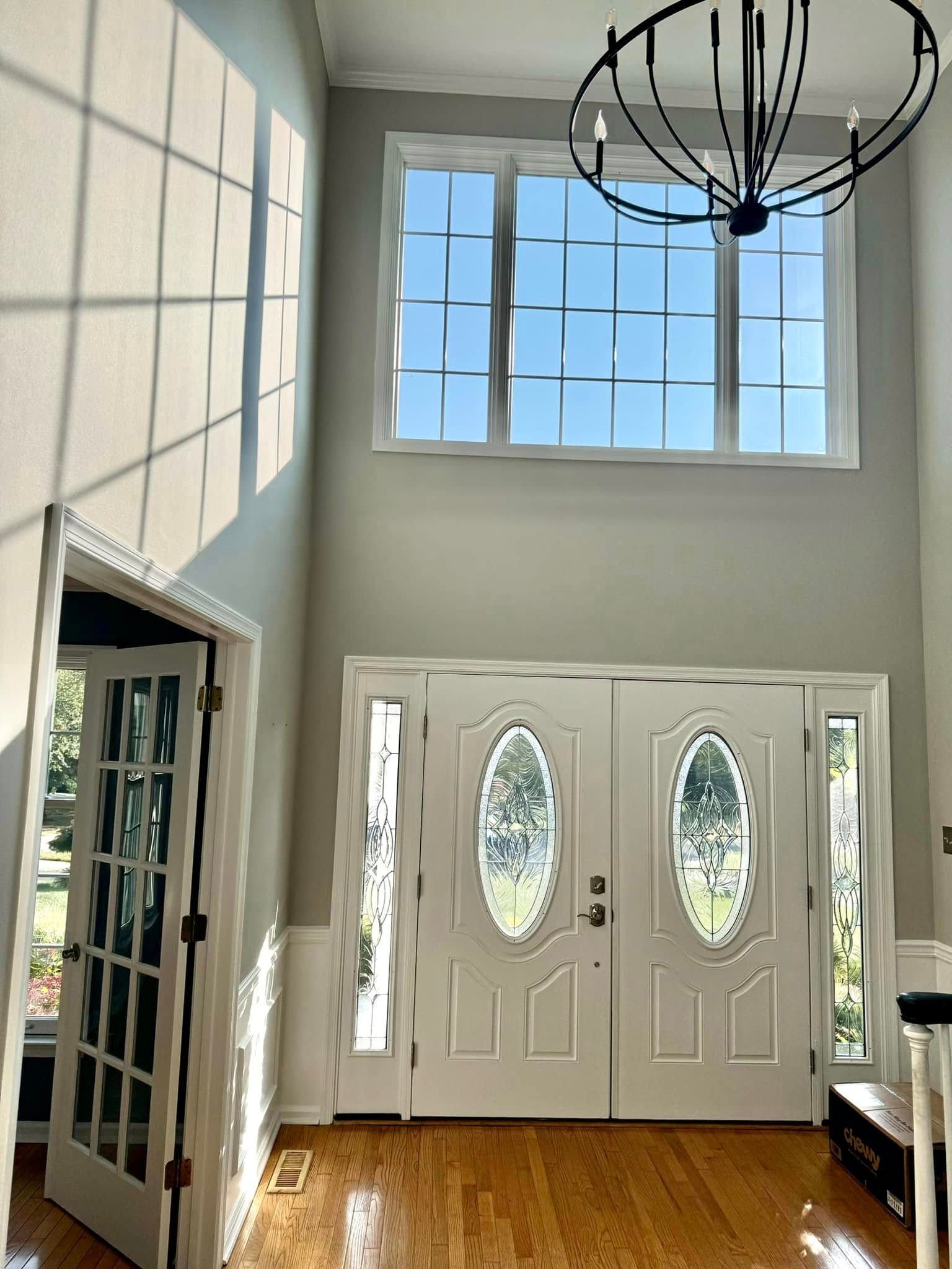 A hallway with two doors and a chandelier hanging from the ceiling