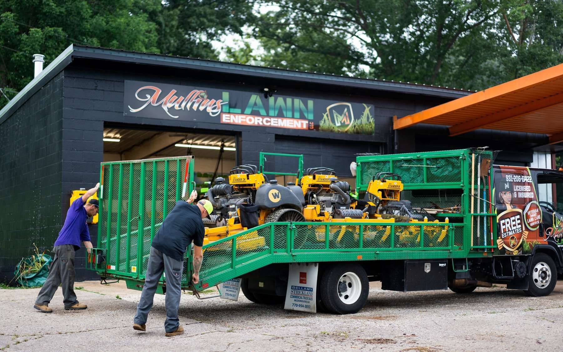 A man is loading a lawn mower onto a tow truck.
