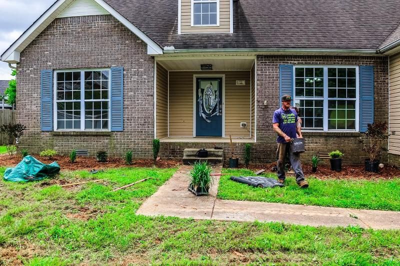 A man is standing in front of a brick house.