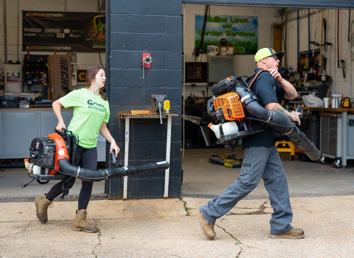 A man and a woman are walking with a blower on their backs.