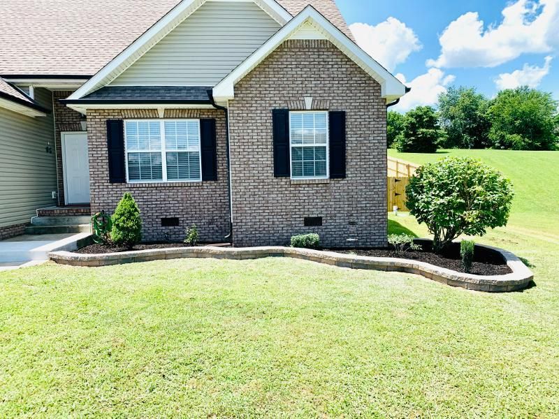 A brick house with a lush green lawn in front of it.