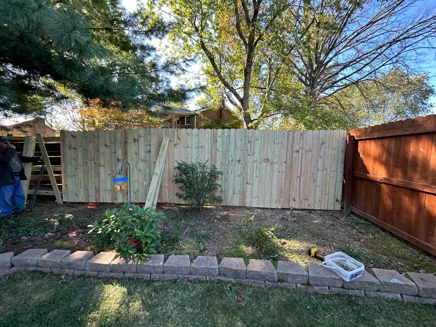 A wooden fence is being built in a backyard.