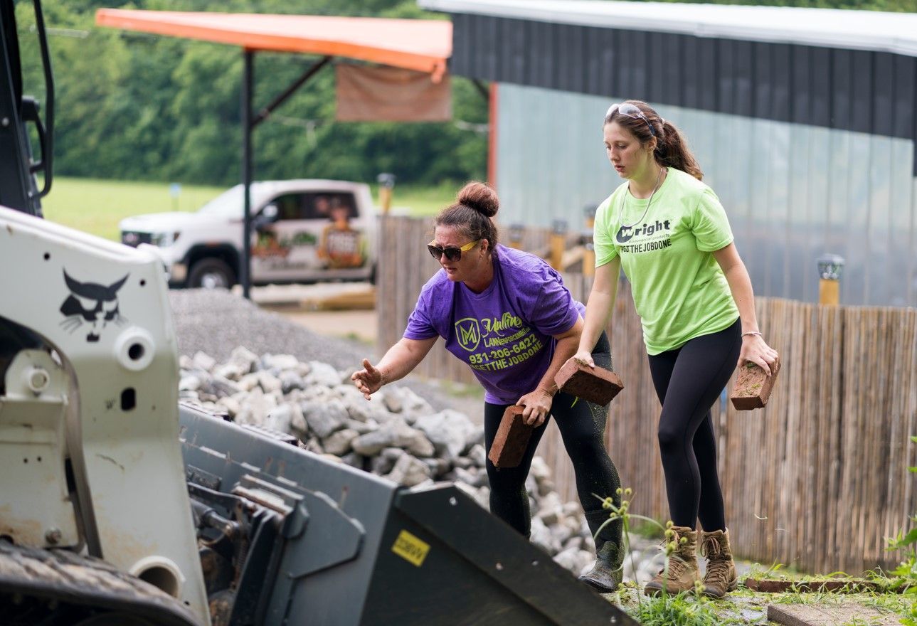 Two women are standing next to a bulldozer.