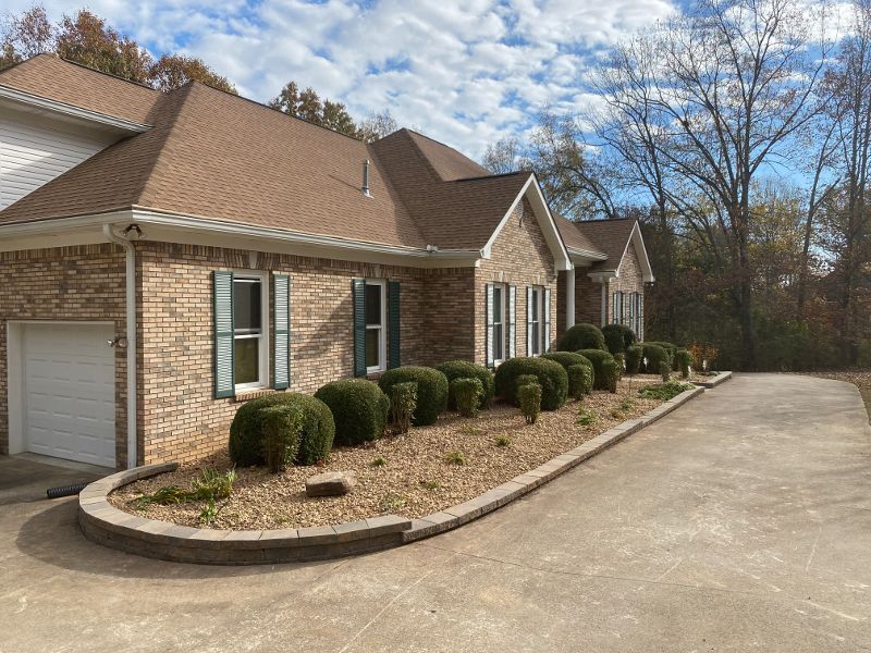A large brick house with a driveway and bushes in front of it.