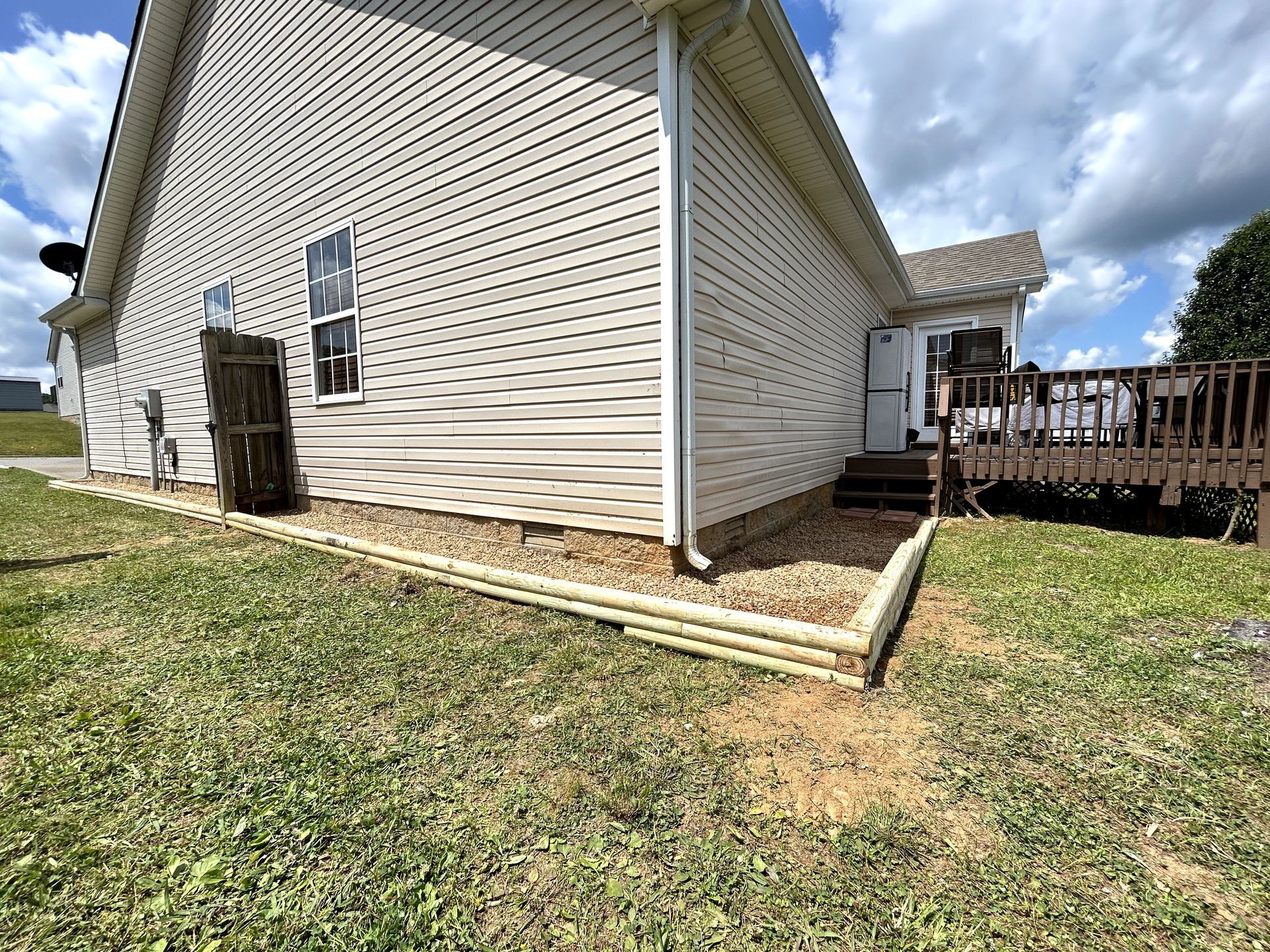 A white house with a wooden deck in the backyard.