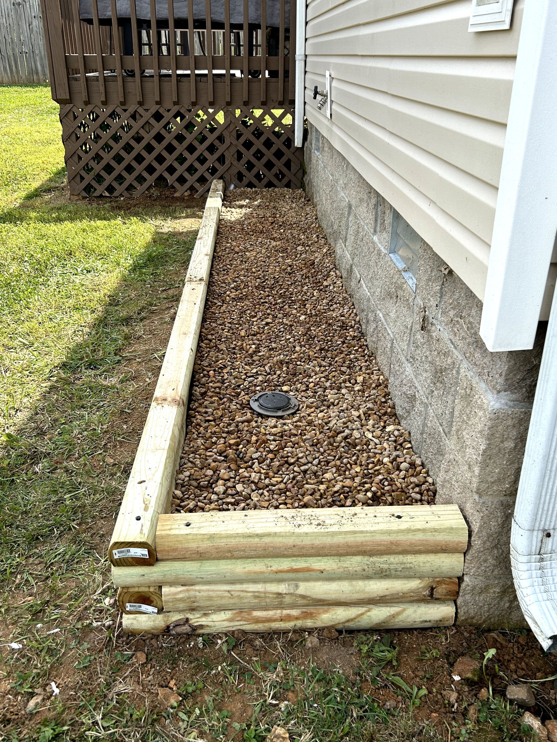 A wooden planter is sitting next to a house.