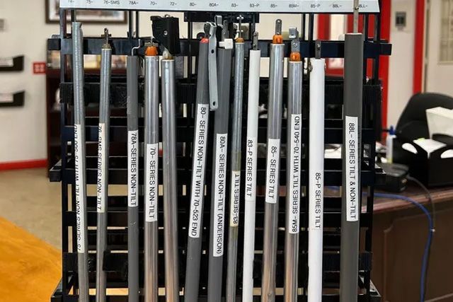 Rows of vertical metal poles with labels in a workshop or storage area