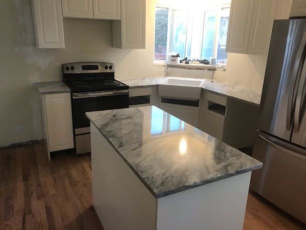 A kitchen with a large island , stove , refrigerator and sink.