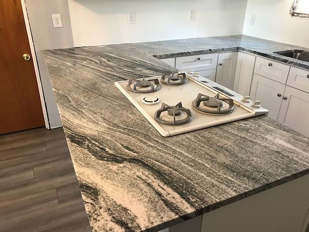 A kitchen with a stove top oven and granite counter tops.