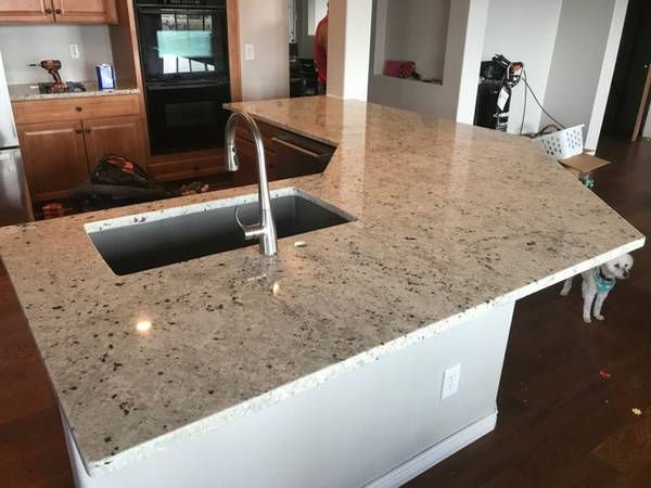 A kitchen with granite counter tops and a stainless steel sink