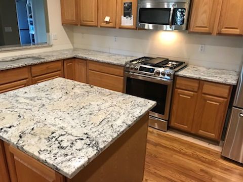 A kitchen with granite counter tops , stainless steel appliances , and wooden cabinets.