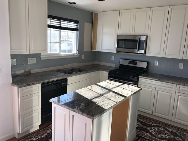 A kitchen with white cabinets , granite counter tops , stainless steel appliances and a large island.