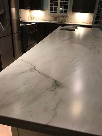 A kitchen with a large white counter top and stainless steel appliances.