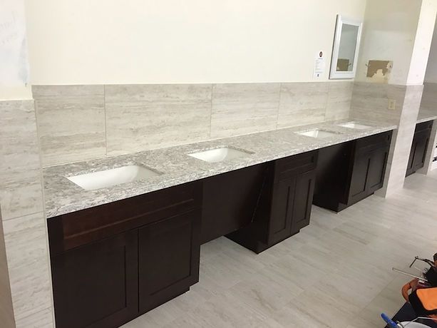 A bathroom with a row of sinks and cabinets