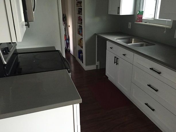 A kitchen with white cabinets and a stove top oven