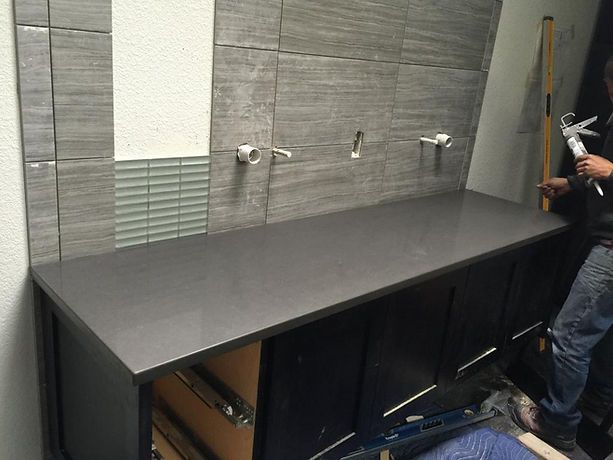 A man is standing next to a counter in a bathroom.