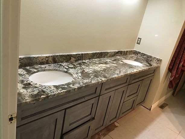 A bathroom with two sinks and granite counter tops.
