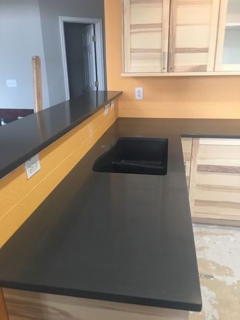 A kitchen with a black counter top and a black sink.