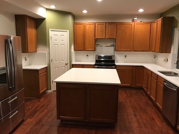 A kitchen with wooden cabinets , stainless steel appliances , and a large island.