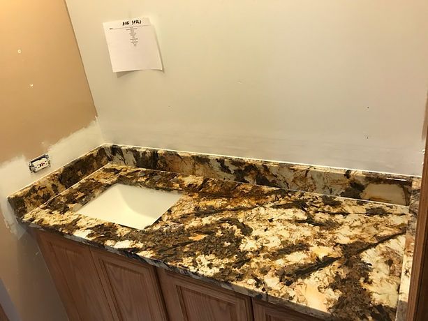 A bathroom vanity with a sink and a granite counter top.