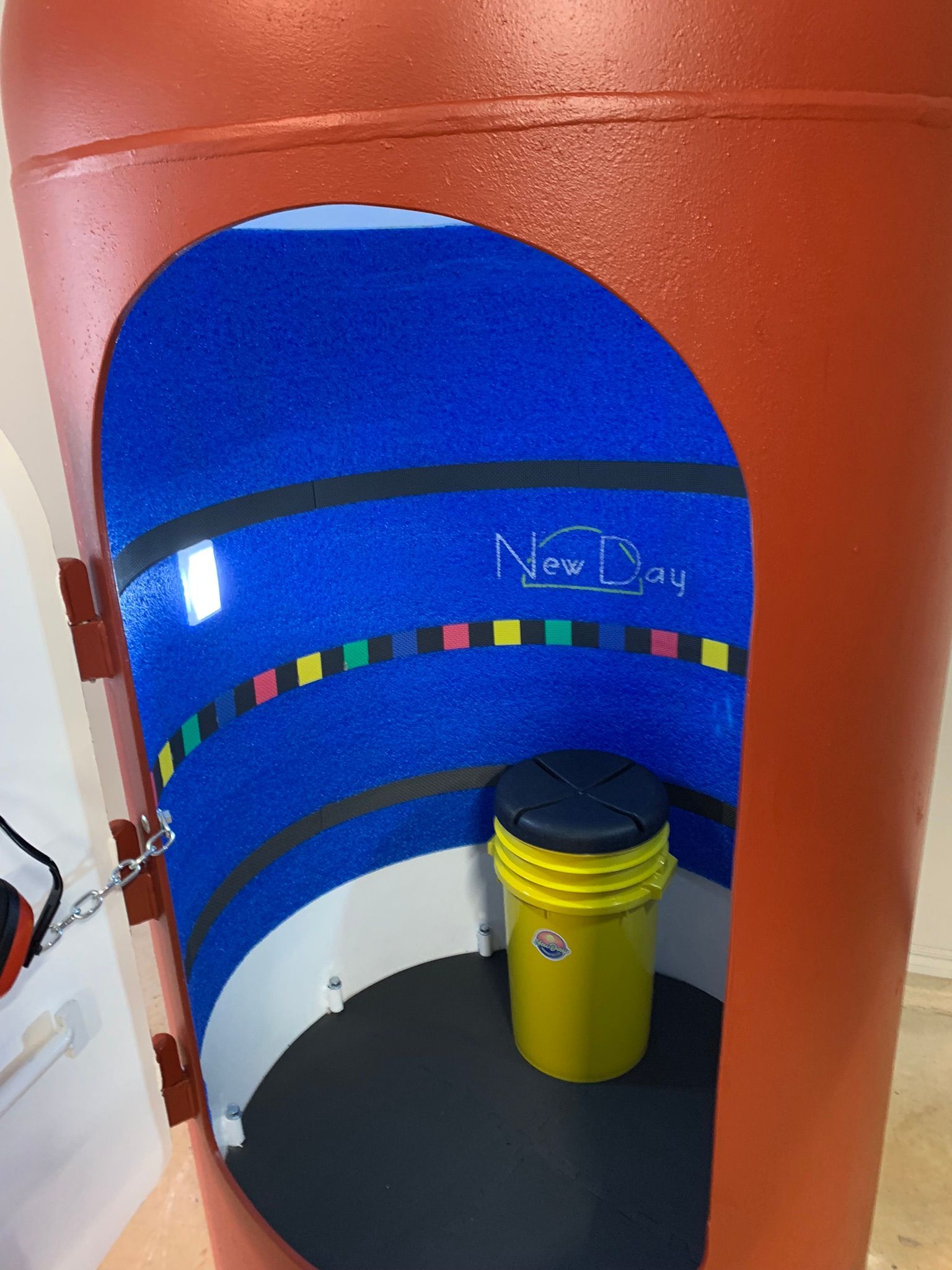 A red shelter with a yellow bucket inside of it that says now day