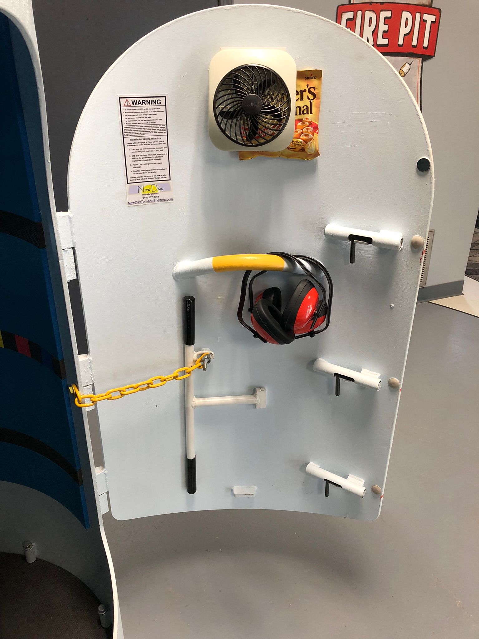 A white shelter door with a fan and ear muffs on it.