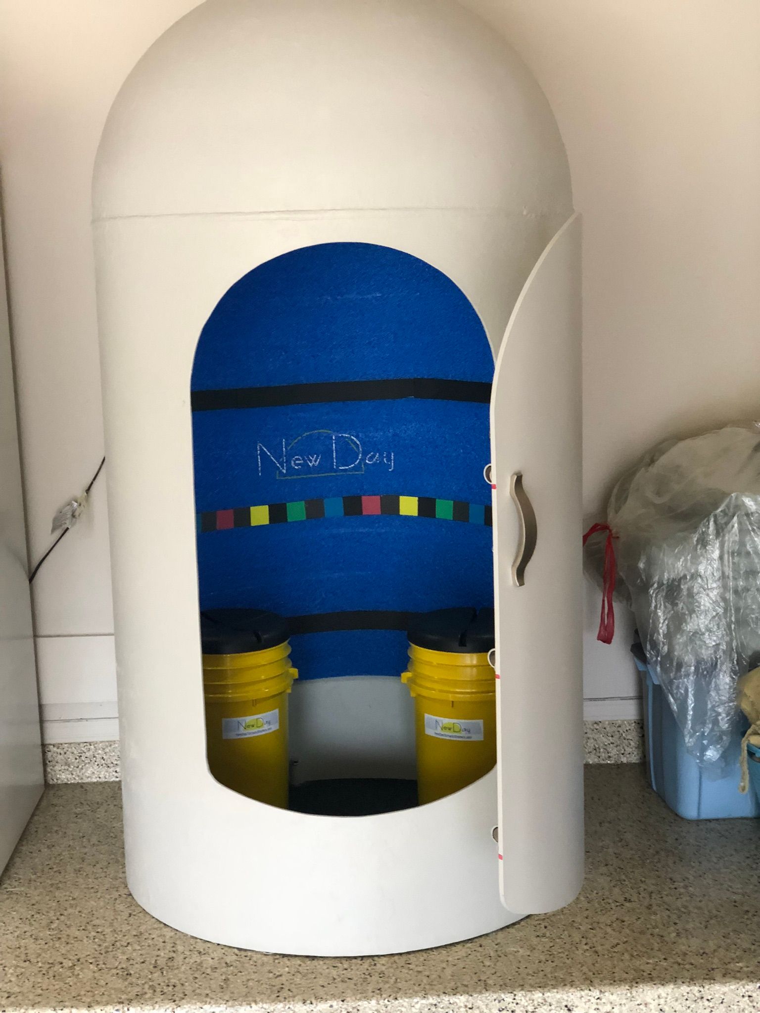 A white shelter with two yellow buckets inside of it