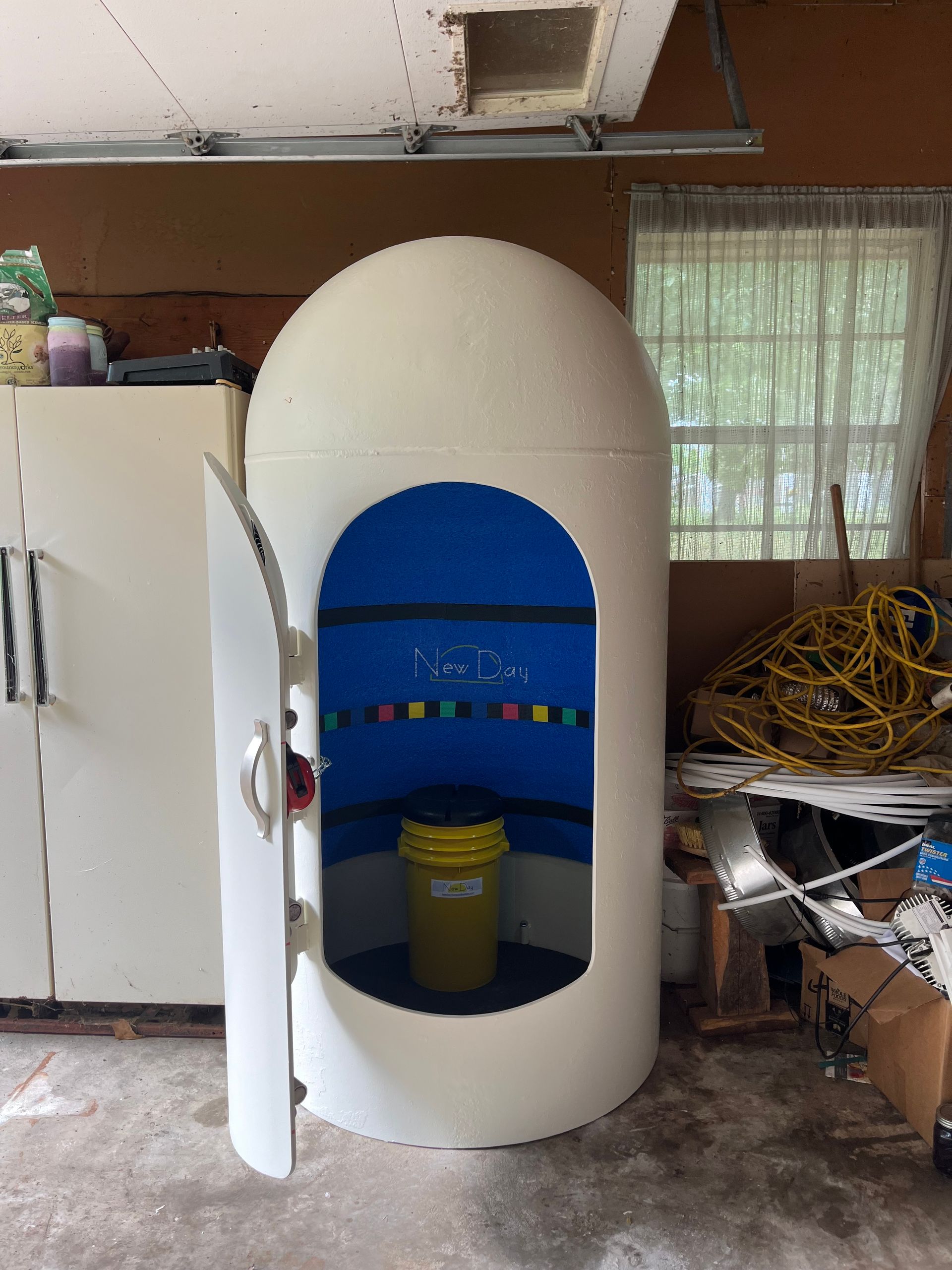 A white shelter with a yellow bucket inside of it in a garage.