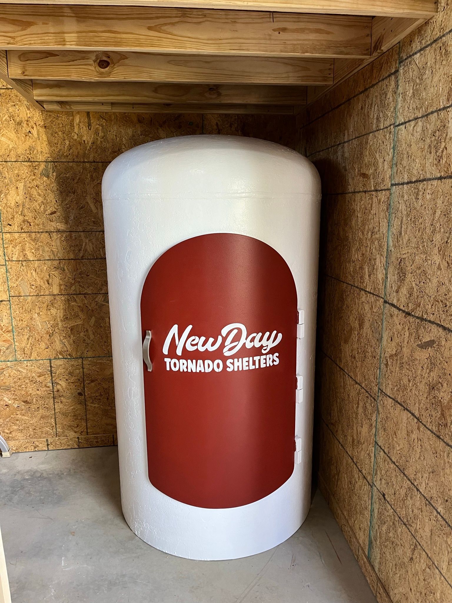 A large white cylinder with a red sticker on it is sitting in a wooden room.