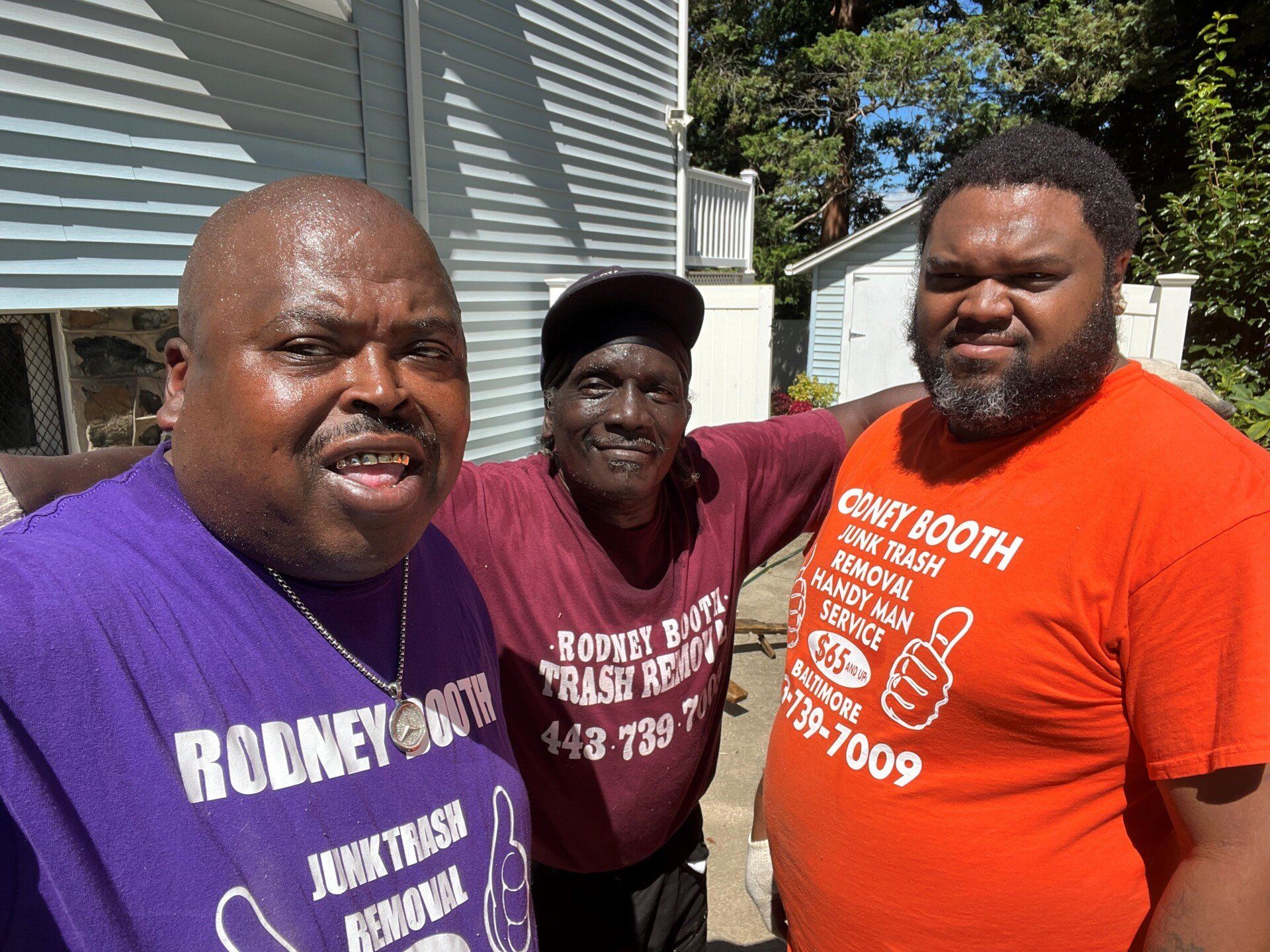 three workers wearing purple, maroon and orange company shirts in a group