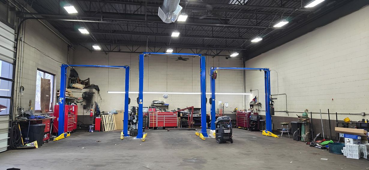 Auto repair shop with two cars on lifts and a mechanic working underneath one vehicle