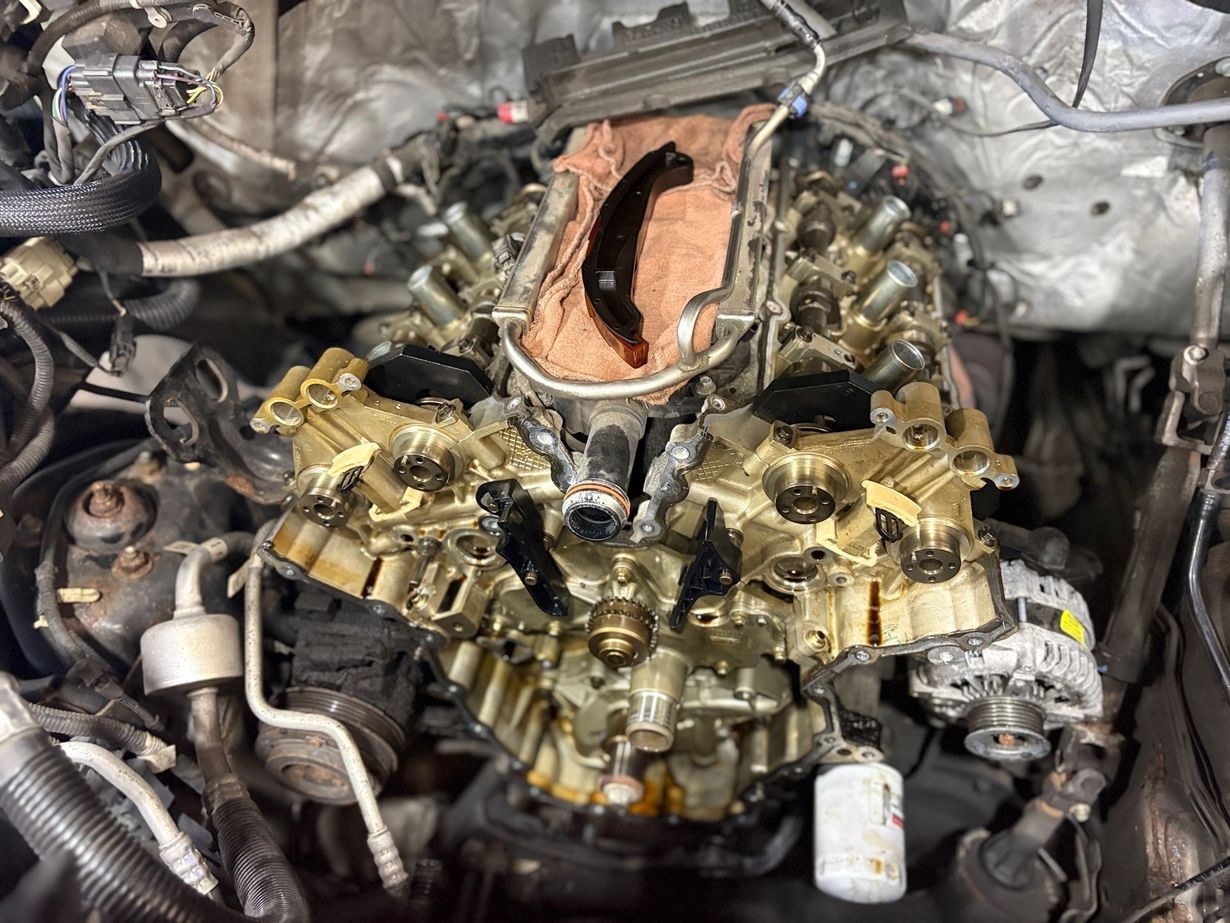 Car engine bay with black components, silver intake manifold, and a red battery cover
