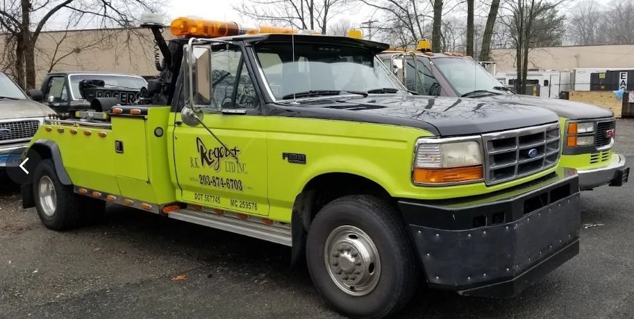 Bright lime-green tow truck with orange light bar parked outdoors on a road