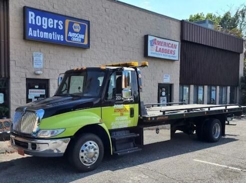 Lime green tow truck parked outside Rogers Automotive and American Lifts shop