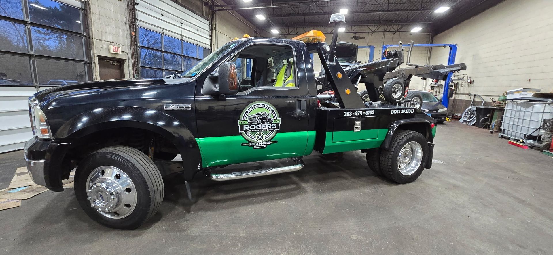 Black pickup truck with green racing graphics in a garage or workshop