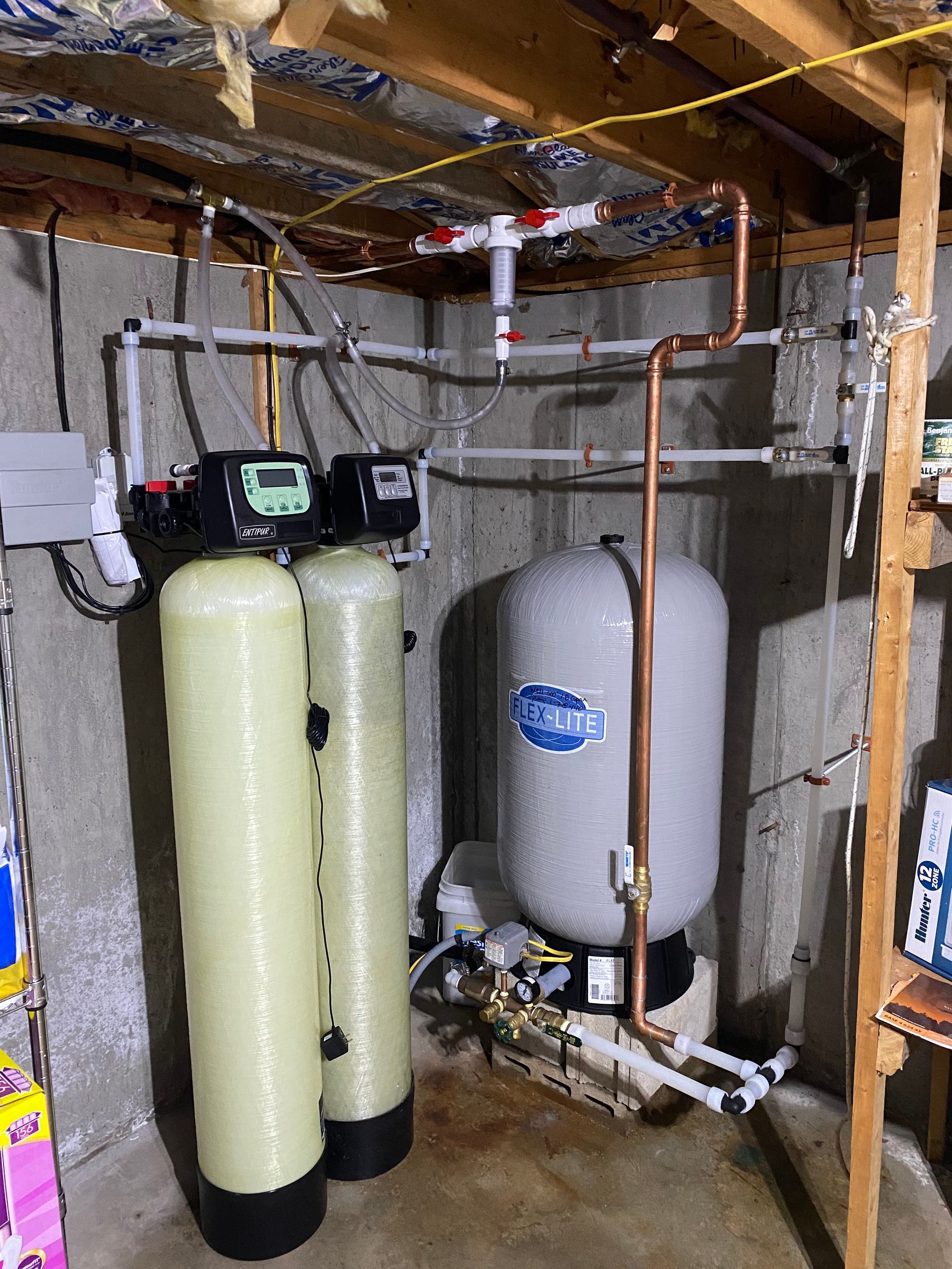 Water treatment system in a basement with tanks, pipes, and control panels.