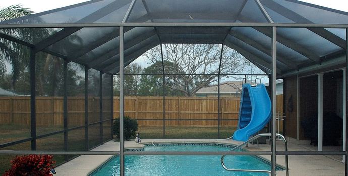 Pool with blue slide inside a screened enclosure.